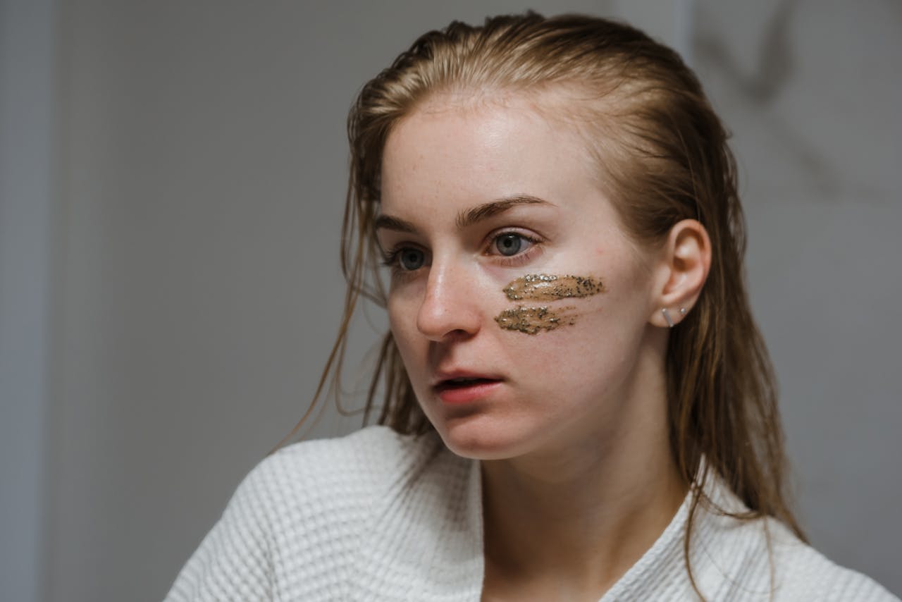 Young woman applies coffee scrub on her face for a refreshing skincare routine.